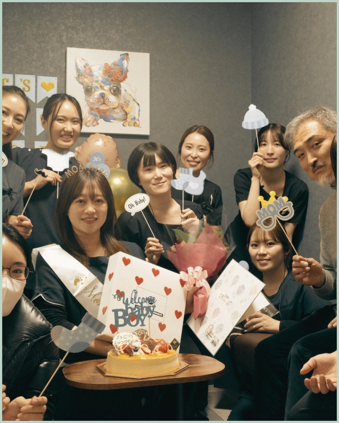 花束やケーキを囲んで笑顔で集まるLa Vie clinicのスタッフたち