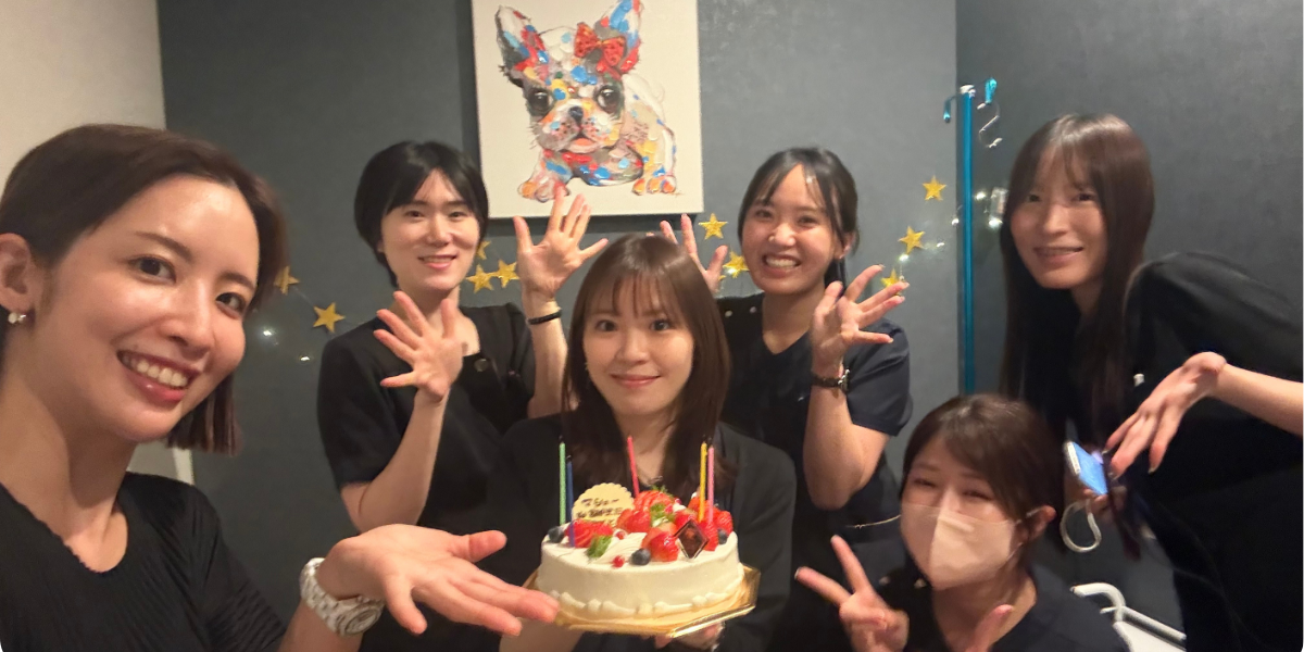 ケーキを囲み、笑顔でお祝いするスタッフたち