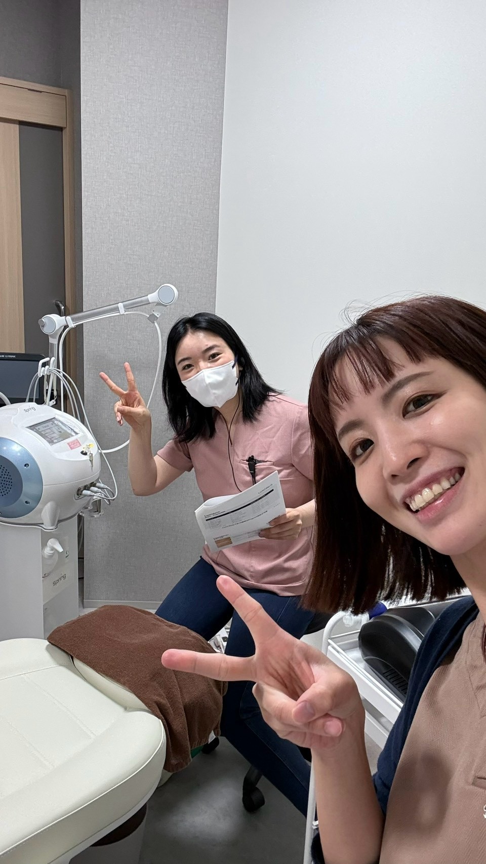 施術室で美容機器と資料を前にポーズをとるスタッフたち